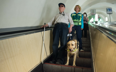 man on escalator with service dog